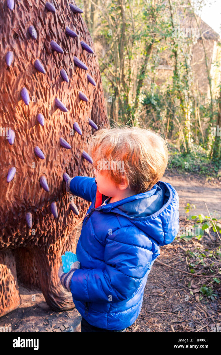 Un jeune garçon de toucher les épines mauve à l'arrière de la sculpture The Gruffalo au Trail, The Gruffalo Horsenden Hill, Greenford, UK Banque D'Images