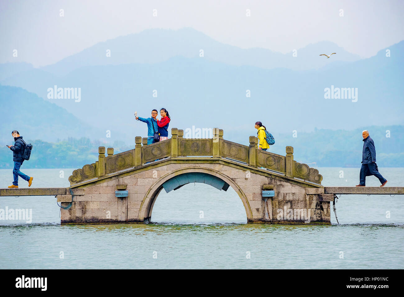 HANGZHOU, CHINE - 23 mars : le peuple chinois à marcher le long d'un pont sur le lac de l'Ouest avec un couple de prendre un autoportrait le 23 mars 2016 à Hangzhou. Banque D'Images