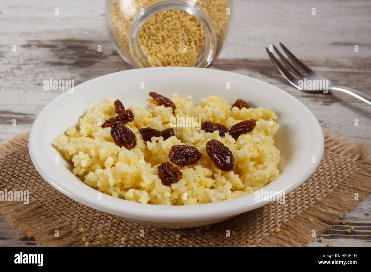 Gruau de millet cuit avec des raisins secs sur plaque blanche, concept d'une saine alimentation, nutrition et petit déjeuner nutritif Banque D'Images