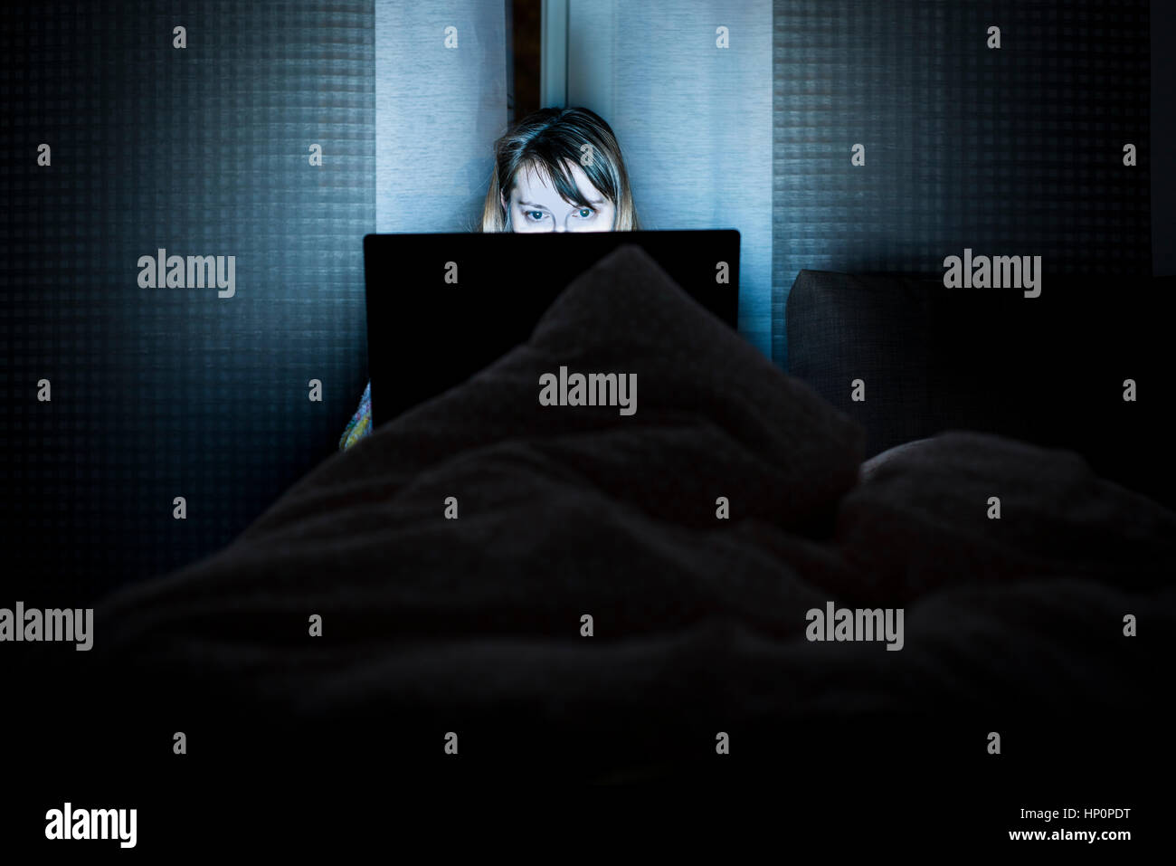 Beautiful smiling woman restent au lit tenir la main sur le clavier de l'ordinateur portable et le type. Regarder les actualités, pour les examens de lecture, réseau social, internet chat su Banque D'Images