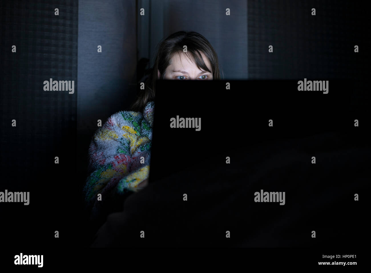 Beautiful smiling woman restent au lit tenir la main sur le clavier de l'ordinateur portable et le type. Regarder les actualités, pour les examens de lecture, réseau social, internet chat su Banque D'Images