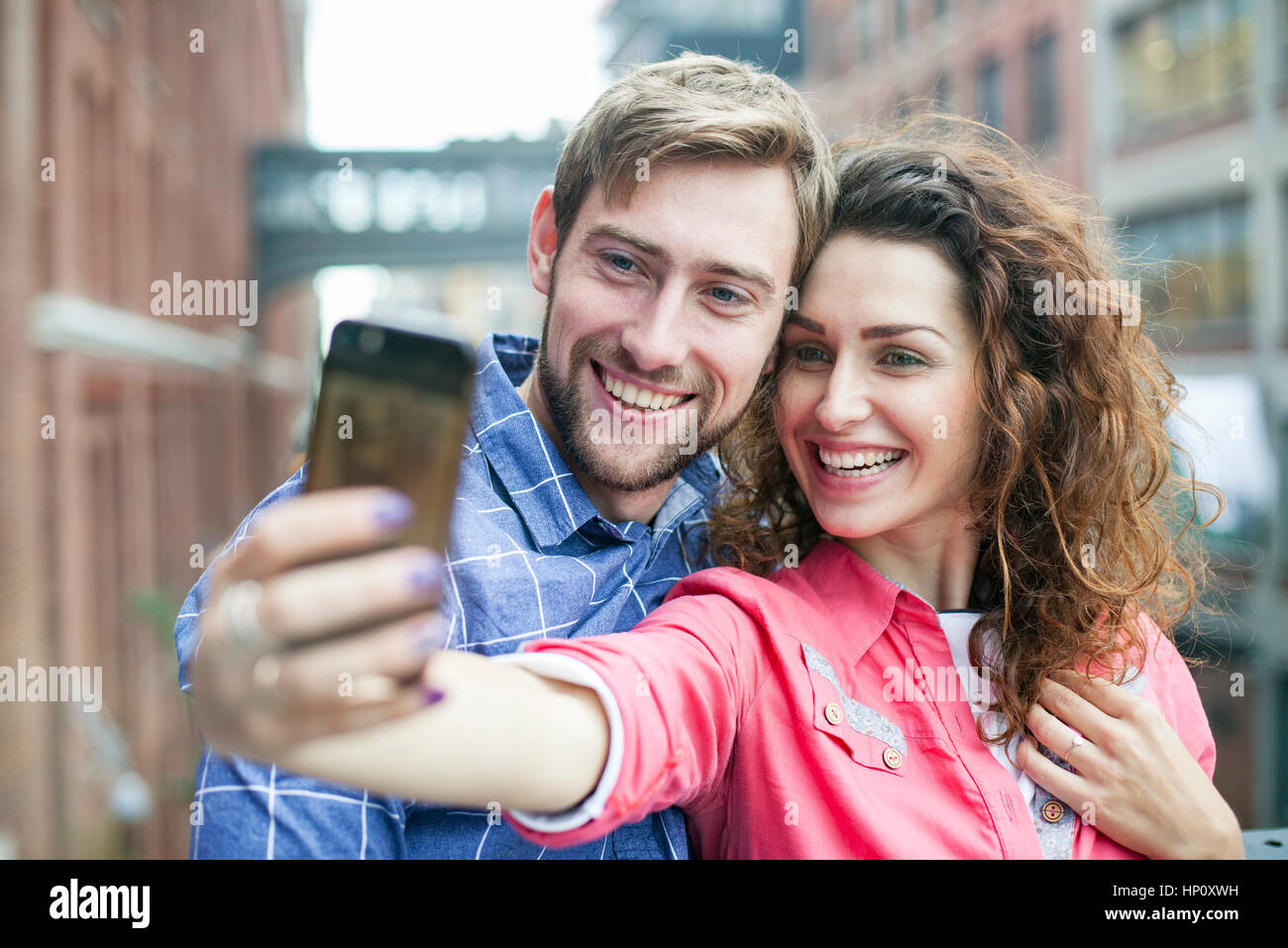 Un couple qui à l'extérieur ensemble selfies Banque D'Images