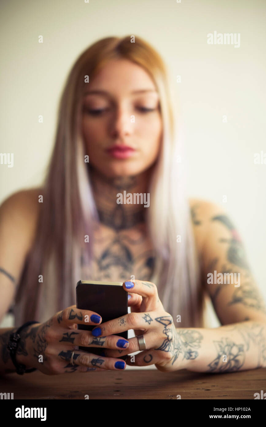 Tattooed Woman using smartphone Banque D'Images