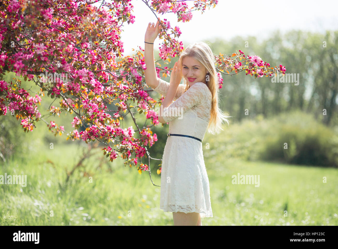 Belle jeune fille belle souriant et profiter au parc pendant la saison des cerisiers en fleur sur un beau printemps Banque D'Images