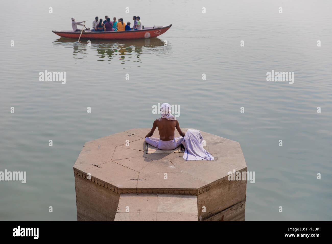 Un homme médite sur le Gange à Varanasi, une des villes les plus saintes de l'Inde. Varanasi est une destination populaire pour les touristes qui fréquentent les écoles de yoga. Banque D'Images