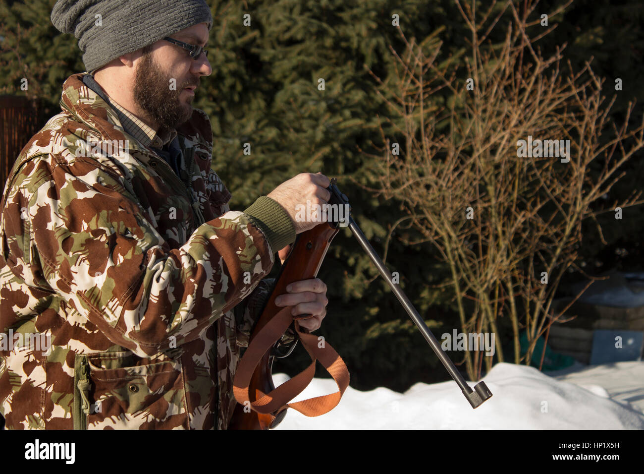 Forêt en hiver homme recharge armes pneumatiques. Hunter tenue de camouflage avec carabine, pistolet pneumatique Banque D'Images