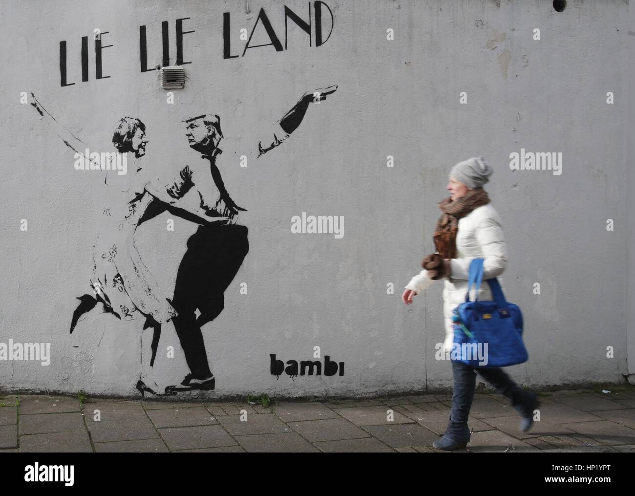 Une femme passe devant un morceau de street art par l'artiste Bambi, intitulé mentir mentir Land - représentant le premier ministre Theresa mai et le président américain, Donald Trump, dansant dans une pose parodiant le film La La Land - à Islington, Londres. Banque D'Images