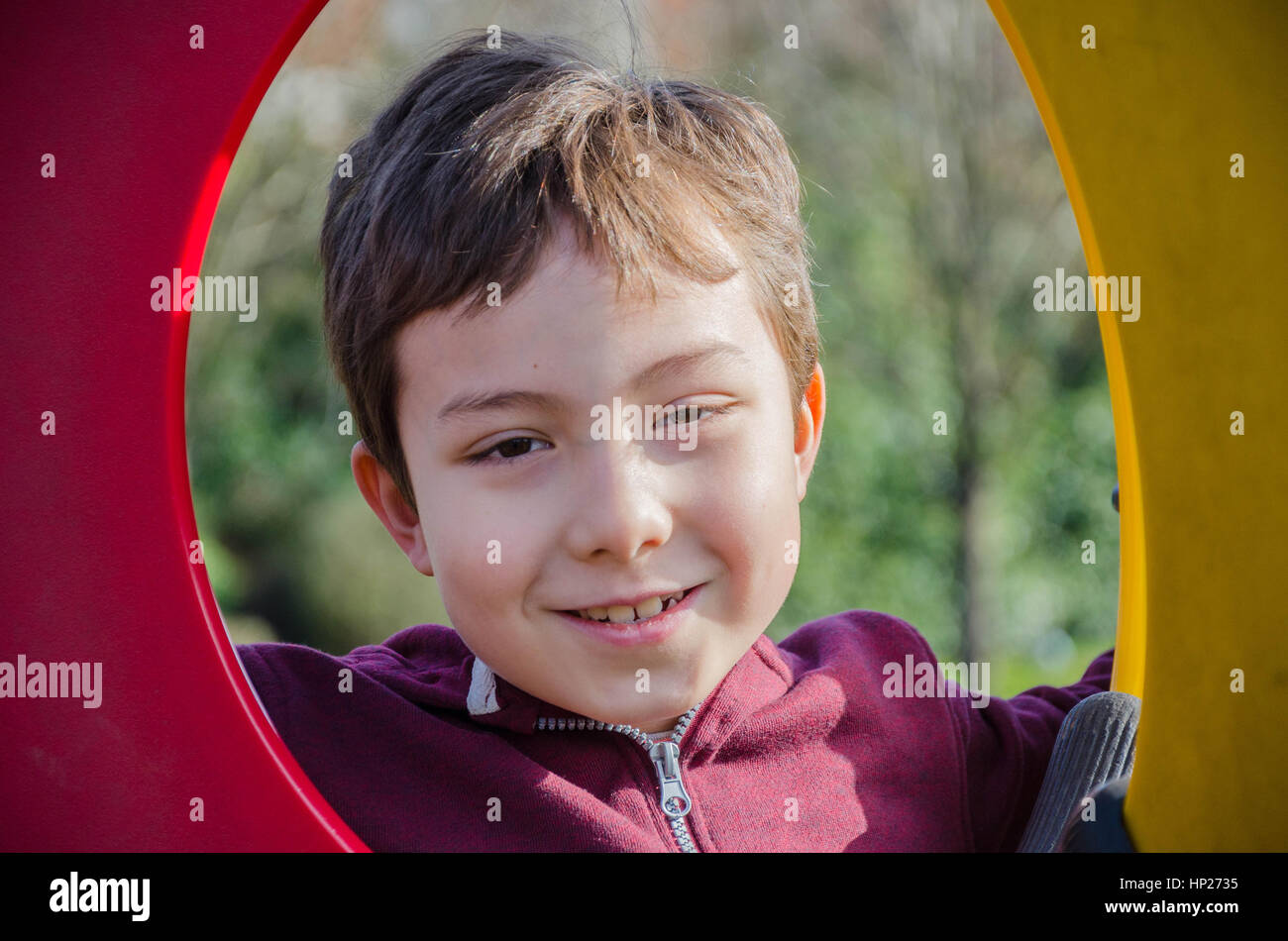 Un jeune garçon pose pour une photo à travers un hublot dans une escalade dans une aire de jeux pour enfants. Banque D'Images