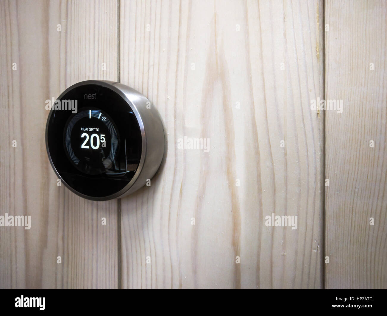Un gros plan d'un thermostat Nest encastrée à un mur en bois blanc Banque D'Images