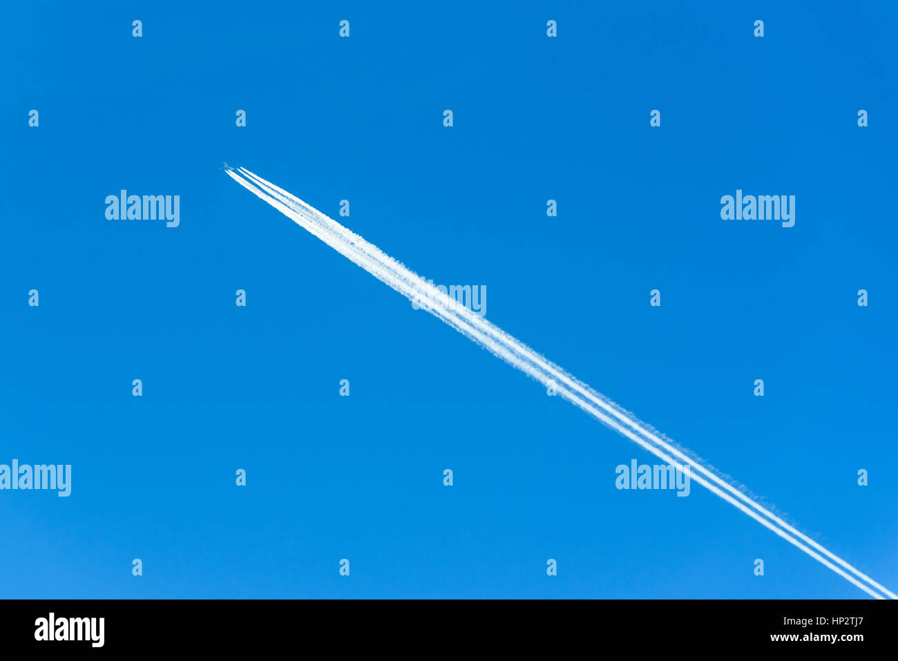 Des traînées de vapeur ou de traînées de après un grand avion à réaction commerciaux en haut ciel bleu. Banque D'Images