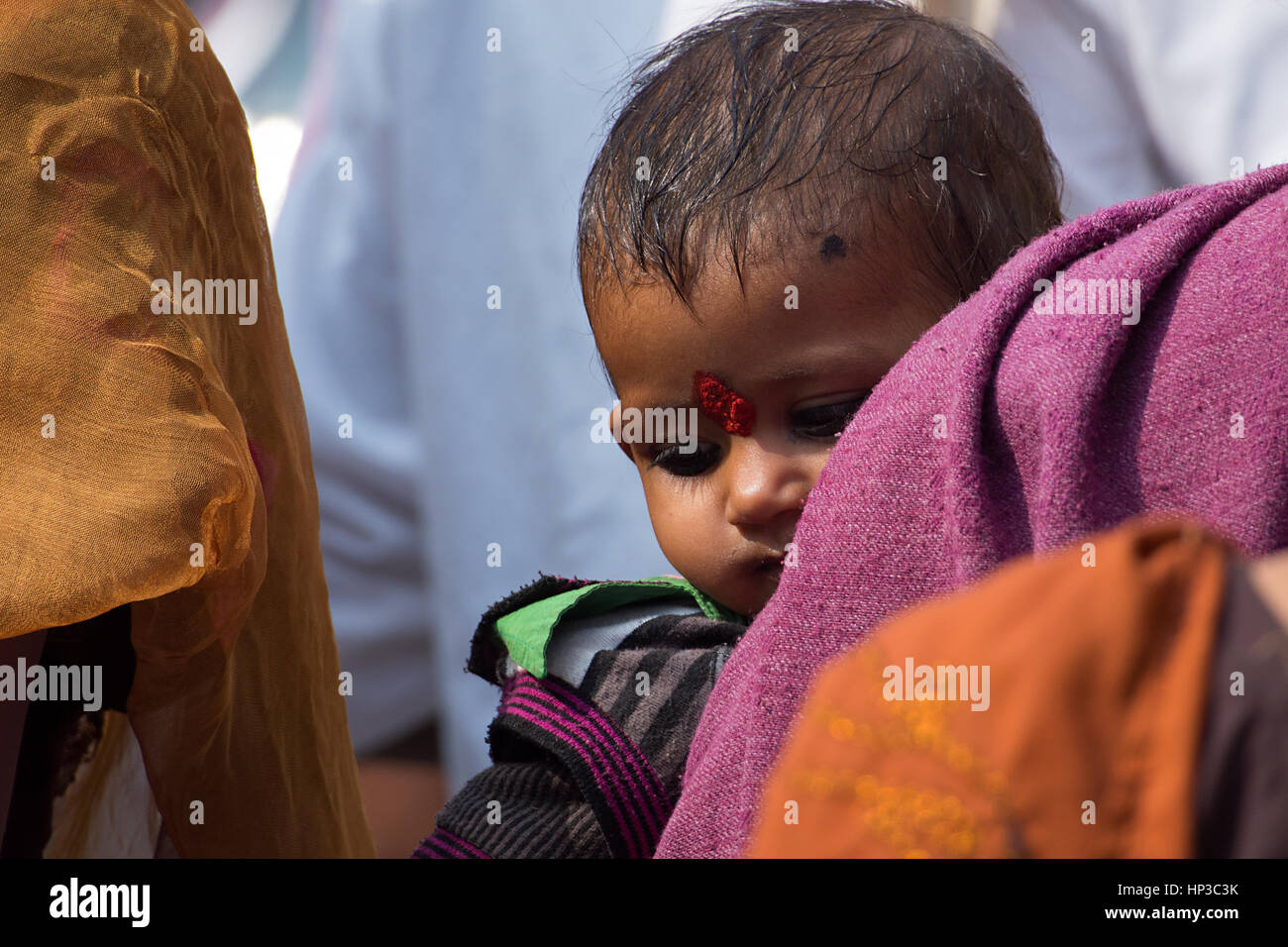 Libre d'un enfant indien avec Big Vermillion marque sur le front, porté par un parent dans la foule Banque D'Images