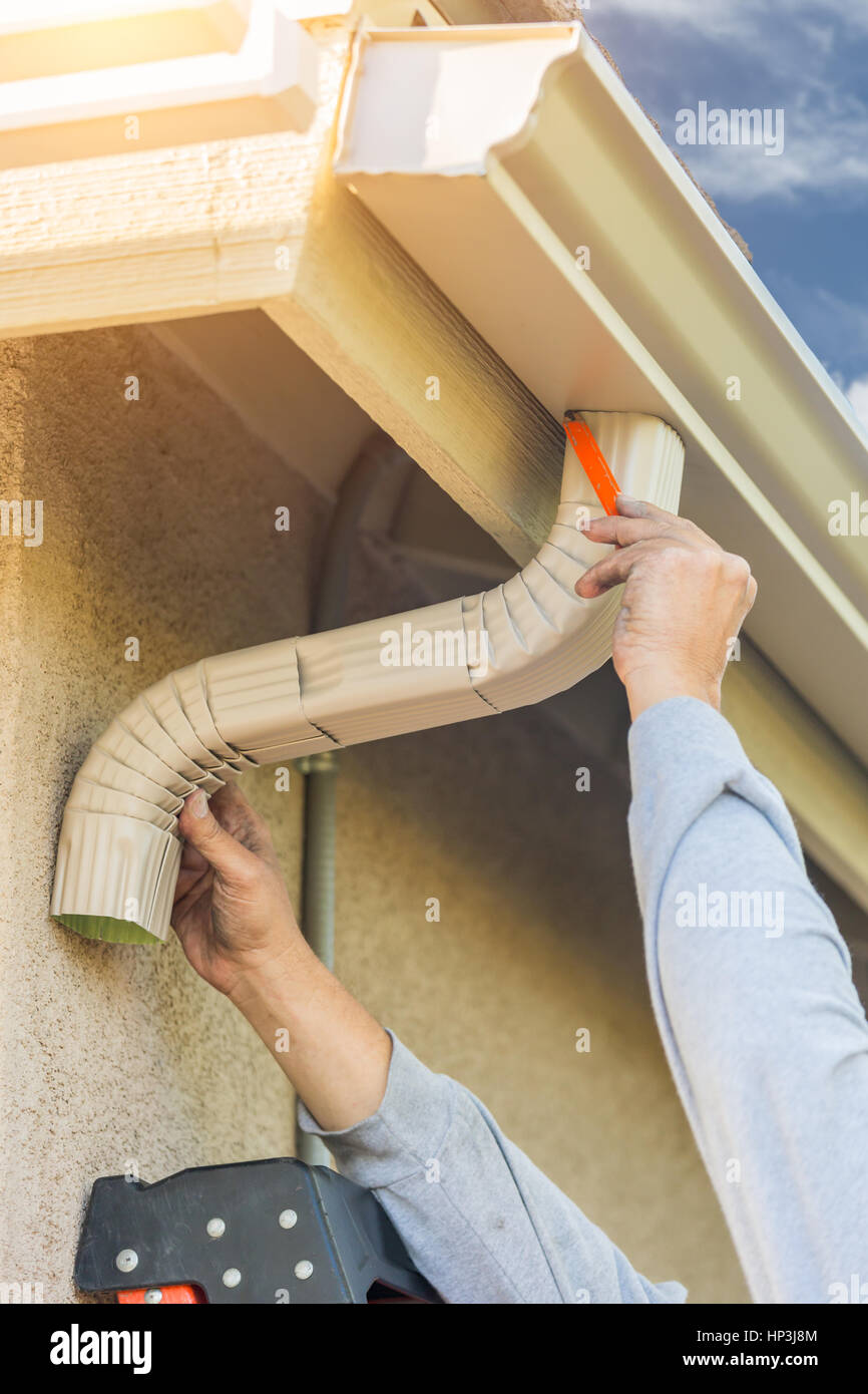 Fixation de gouttière aluminium travailleur et le bas de la goulotte de chambre. Banque D'Images