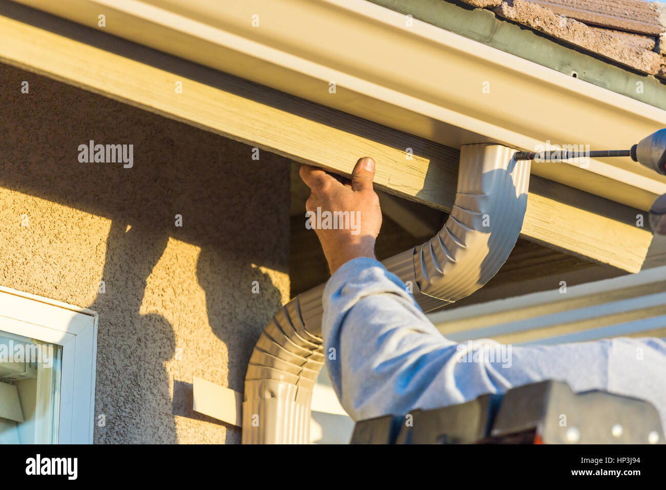 Fixation de gouttière aluminium travailleur et le bas de la goulotte de chambre. Banque D'Images