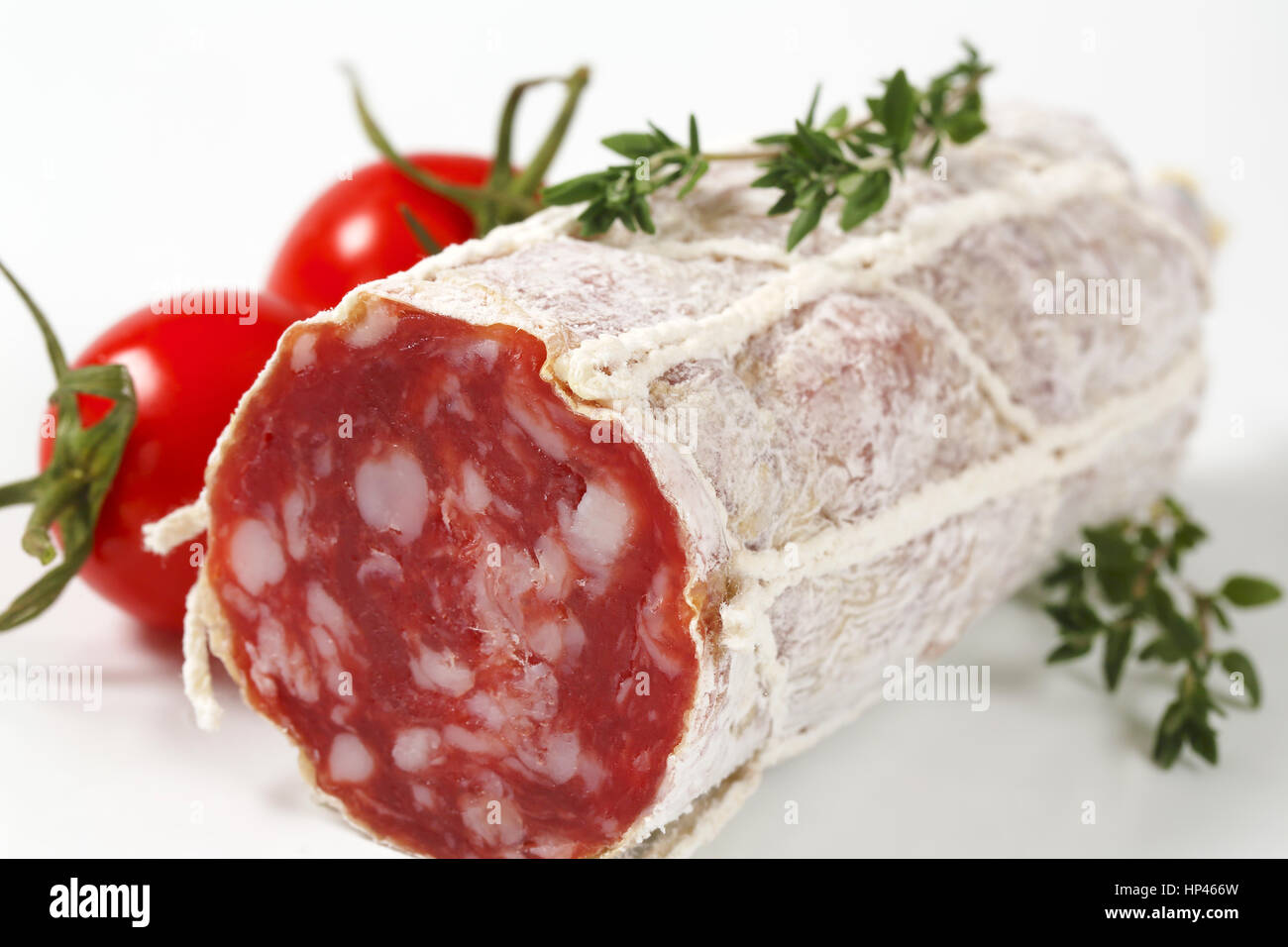 Détail de moitié français salami sec, tomates cerises et thym Banque D'Images