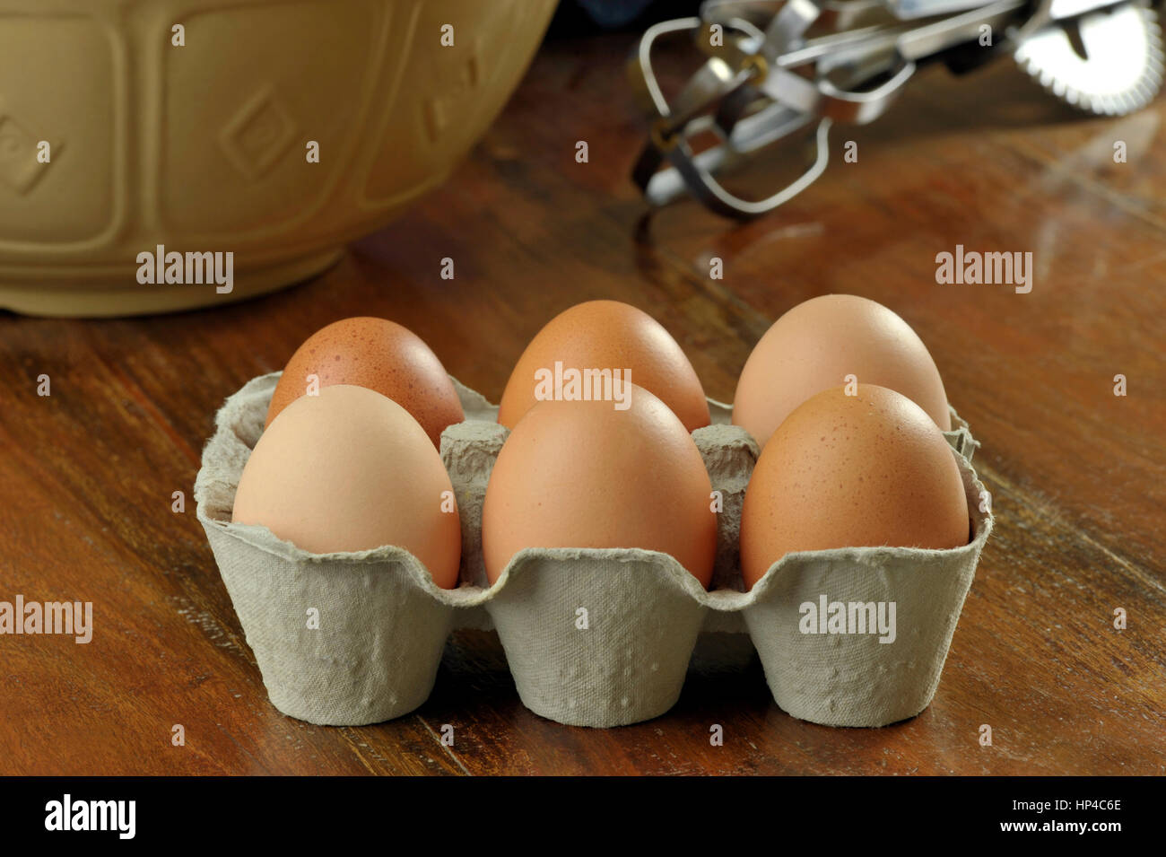 Table de cuisine avec free range oeufs brun dans un papier recyclé moulé ou en cellulose moulée et d'emballage en carton fort d'oeufs de poule avec fouet. Banque D'Images