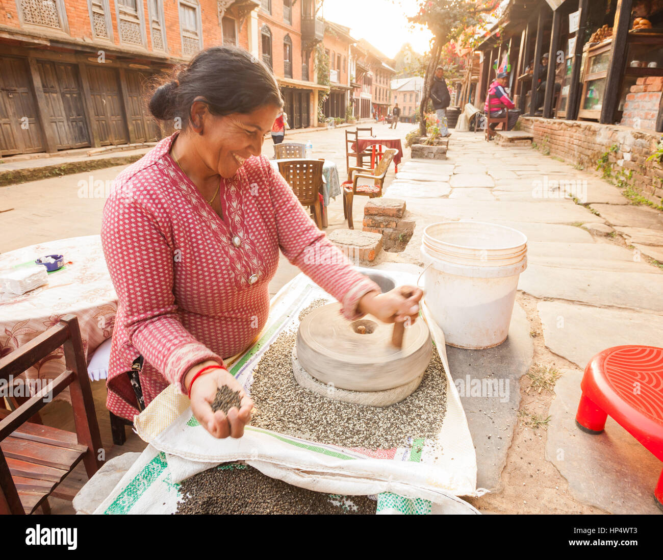 Newari meulage femme dal (secs, légumineuses) split avec une meule à main, Bandipur Bazaar, Népal Banque D'Images