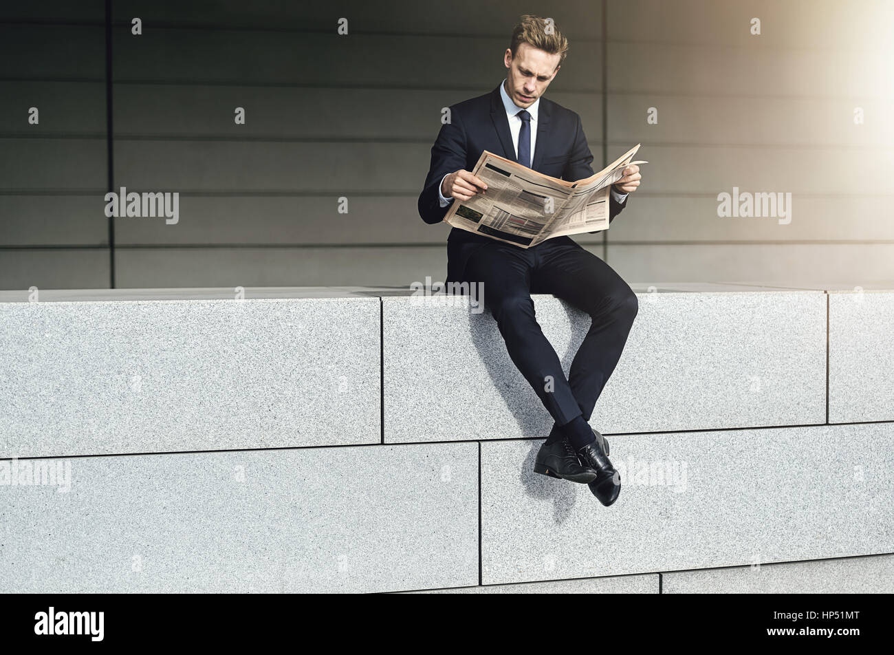 Cool man se trouve sur un mur de briques avec du papier journal Banque D'Images