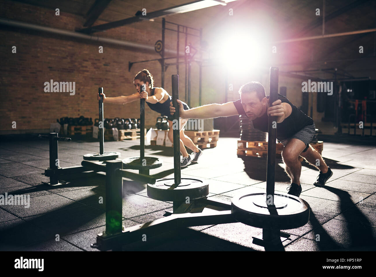 L'homme et la femme poussant avec bogies dur disques de poids. L'intérieur horizontal tourné Banque D'Images