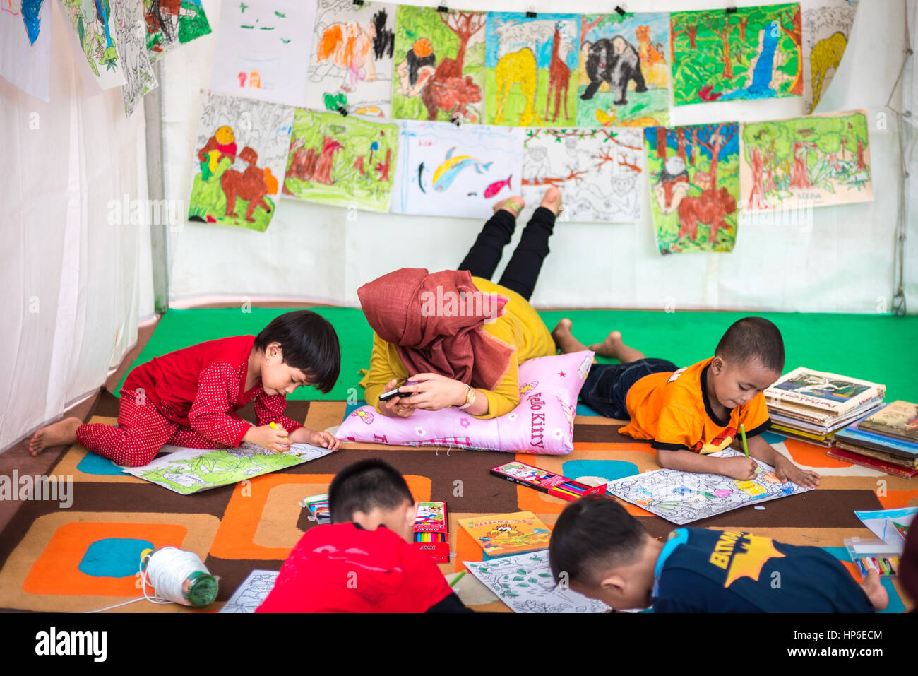Jakarta, Indonésie: Les enfants d'âge préscolaire dessinant des images sur le thème de la conservation de la nature par des crayons de couleur sur des papiers à un stand, lors d'un événement Greenpeace. Banque D'Images