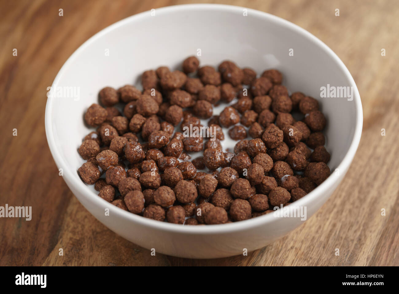 Boules de céréales au chocolat avec du lait dans un bol blanc pour le petit-déjeuner sur la table en bois, l'accent peu profondes Banque D'Images