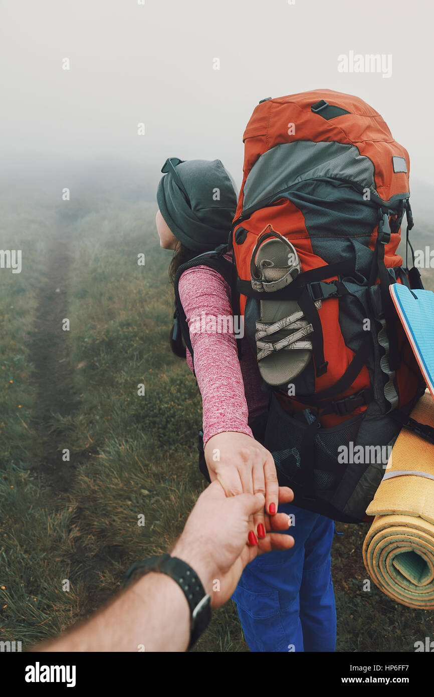 Brave femme voyageur directeurs dans le brouillard dans les montagnes. Suivez-moi. Homme Femme tenant à la main et d'aller dans les montagnes. Banque D'Images