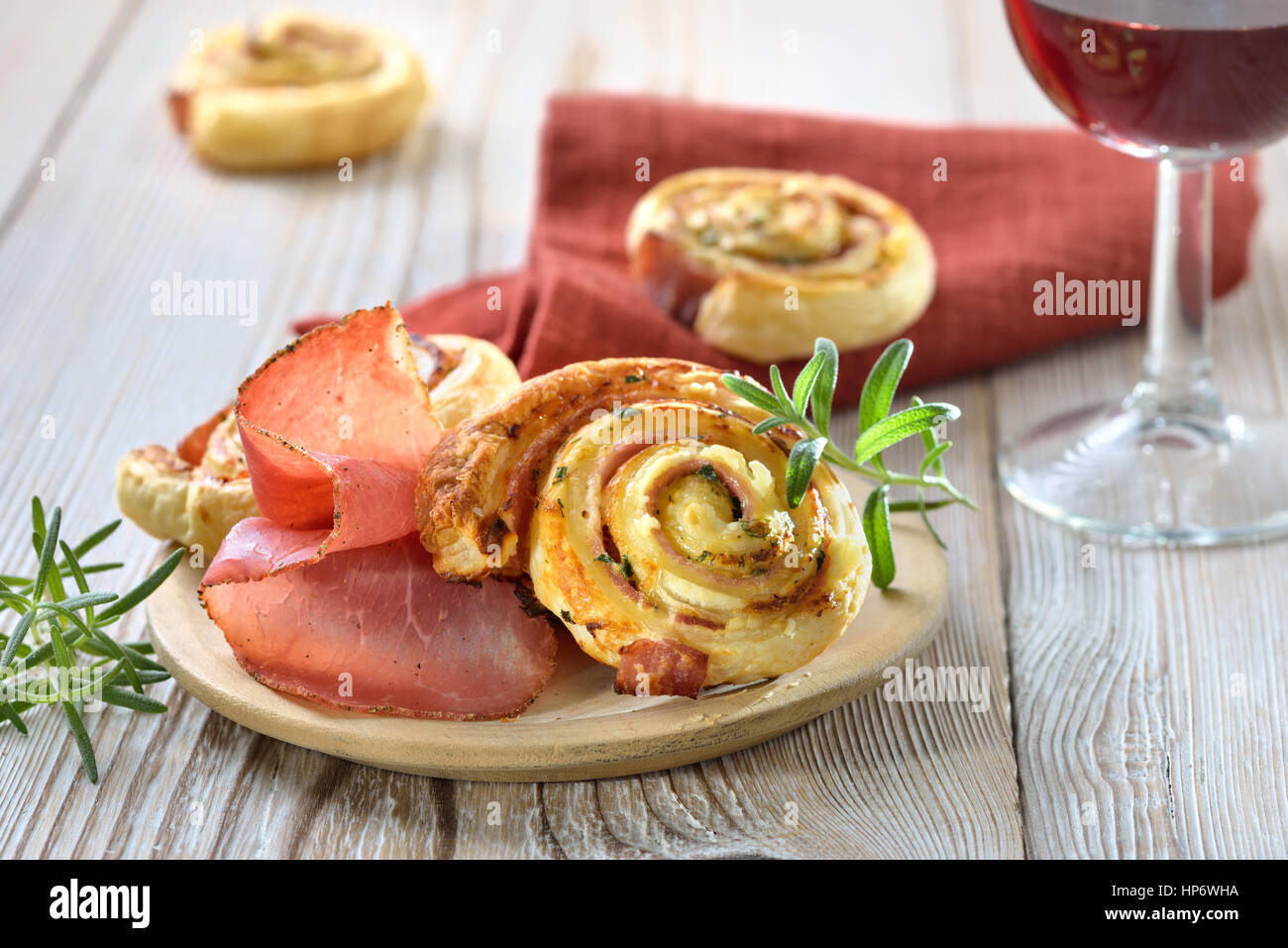 Rouleaux au four pâte feuilletée copieux avec du jambon, fromage à la crème,  le parmesan et les herbes ; servi avec un verre de vin rouge Photo Stock -  Alamy