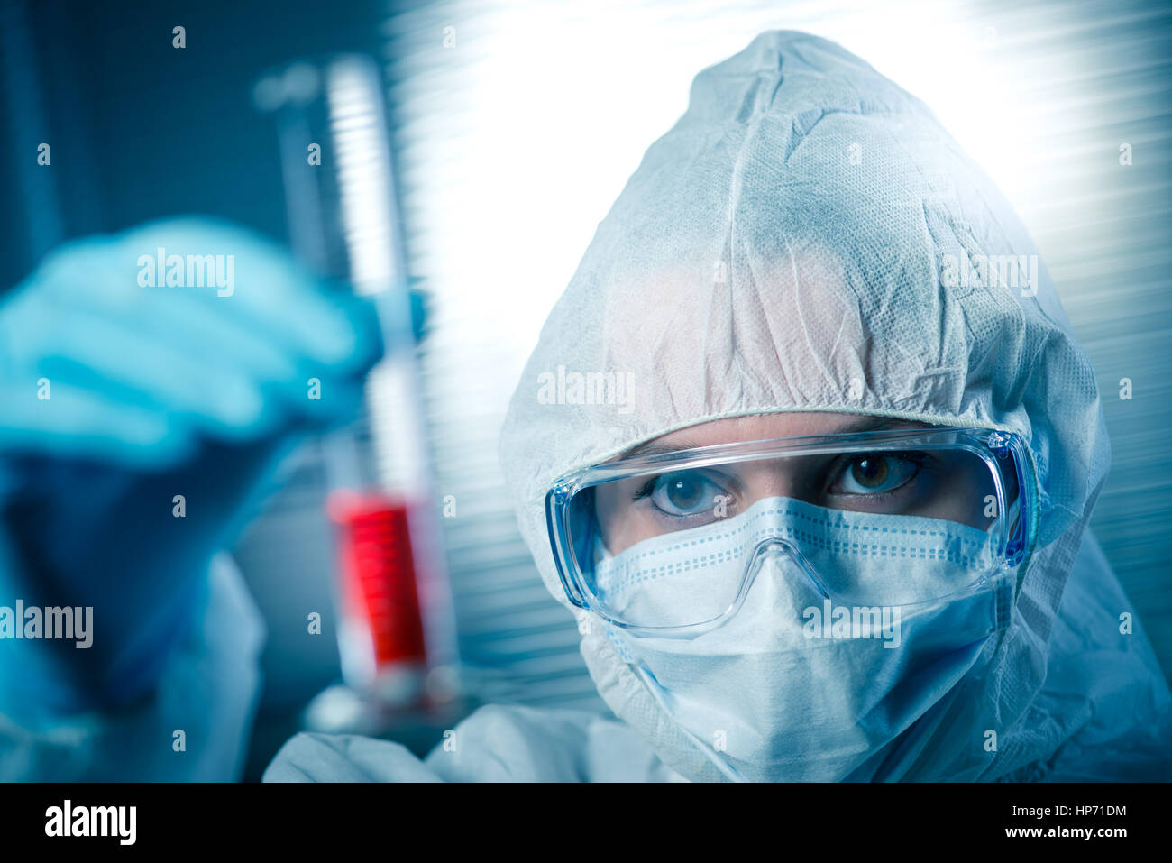 Chercheur en tenue de protection contre les matières dangereuses de l'examen d'un tube à essai dans le laboratoire chimique. Banque D'Images