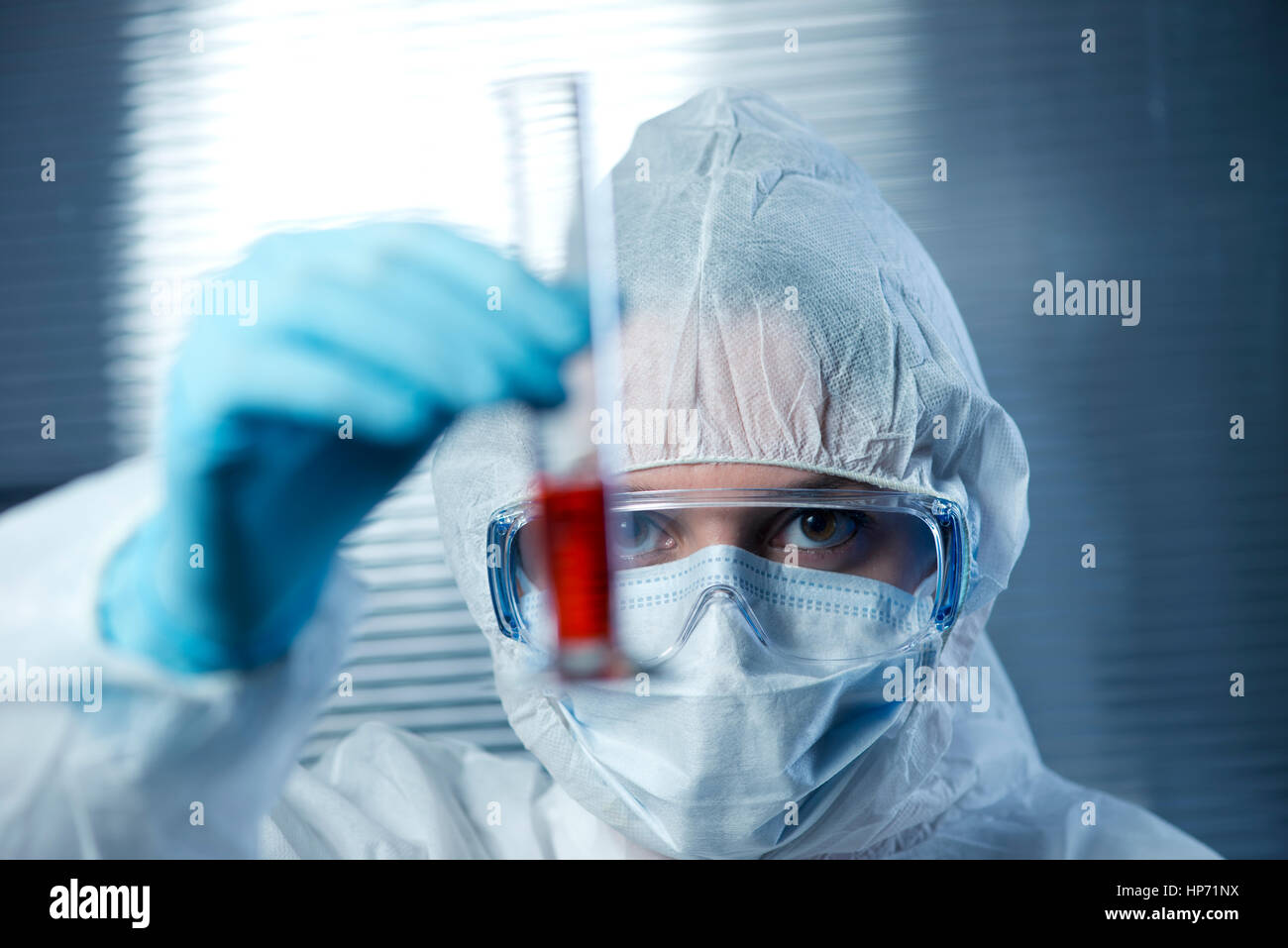 Porter des vêtements protecteurs et scientifique de l'examen d'un tube à essai. Banque D'Images