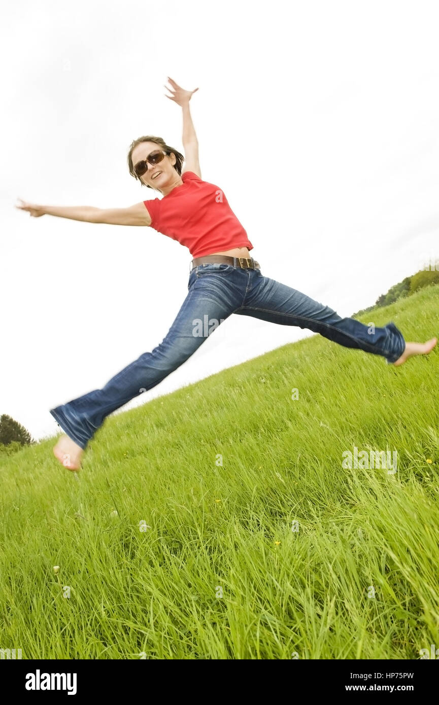 Parution du modèle, Junge Frau, agile, 30, springt in der Wiese - woman in meadow Banque D'Images