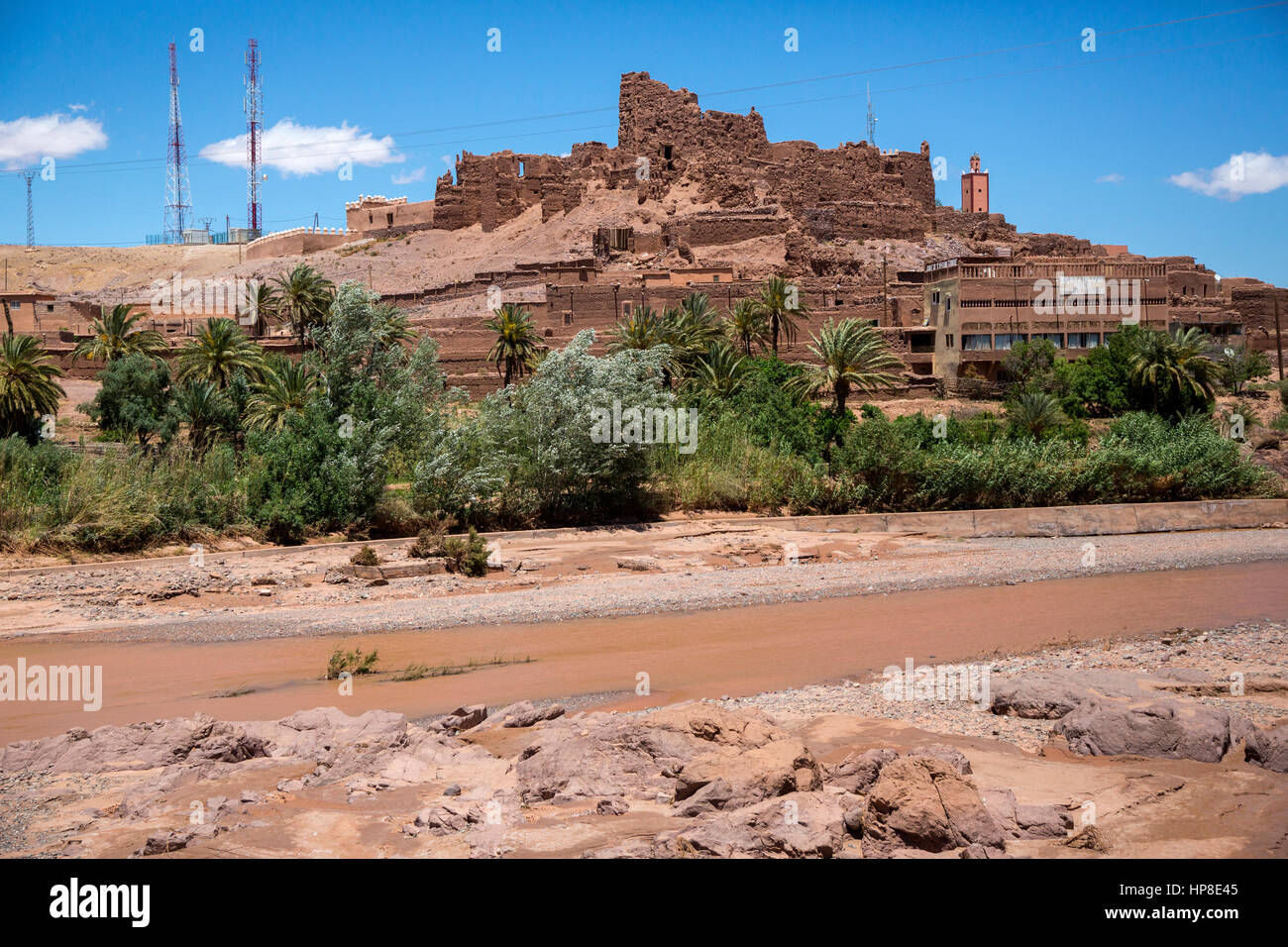 Montagnes de l'Atlas, au Maroc. Vieux Ksar en ruine, des immeubles modernes en premier plan, les tours de relais de communications sur une colline. Banque D'Images