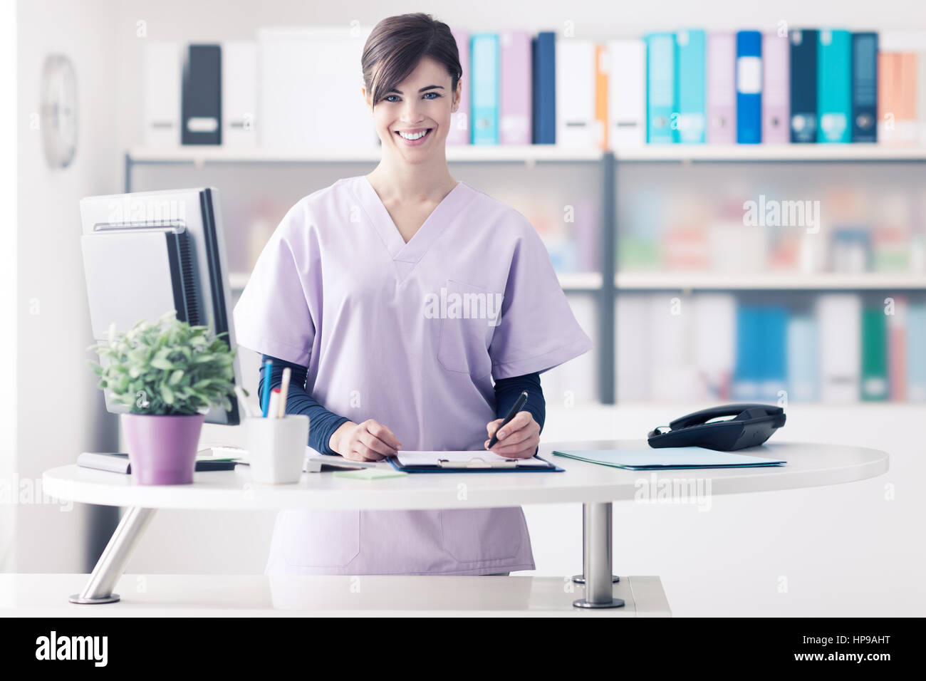 Médecin femme portant un maquis et travaillant à l'hôpital la réception, elle est l'écriture d'un rapport médical sur un presse-papiers et du rendez-vous Banque D'Images