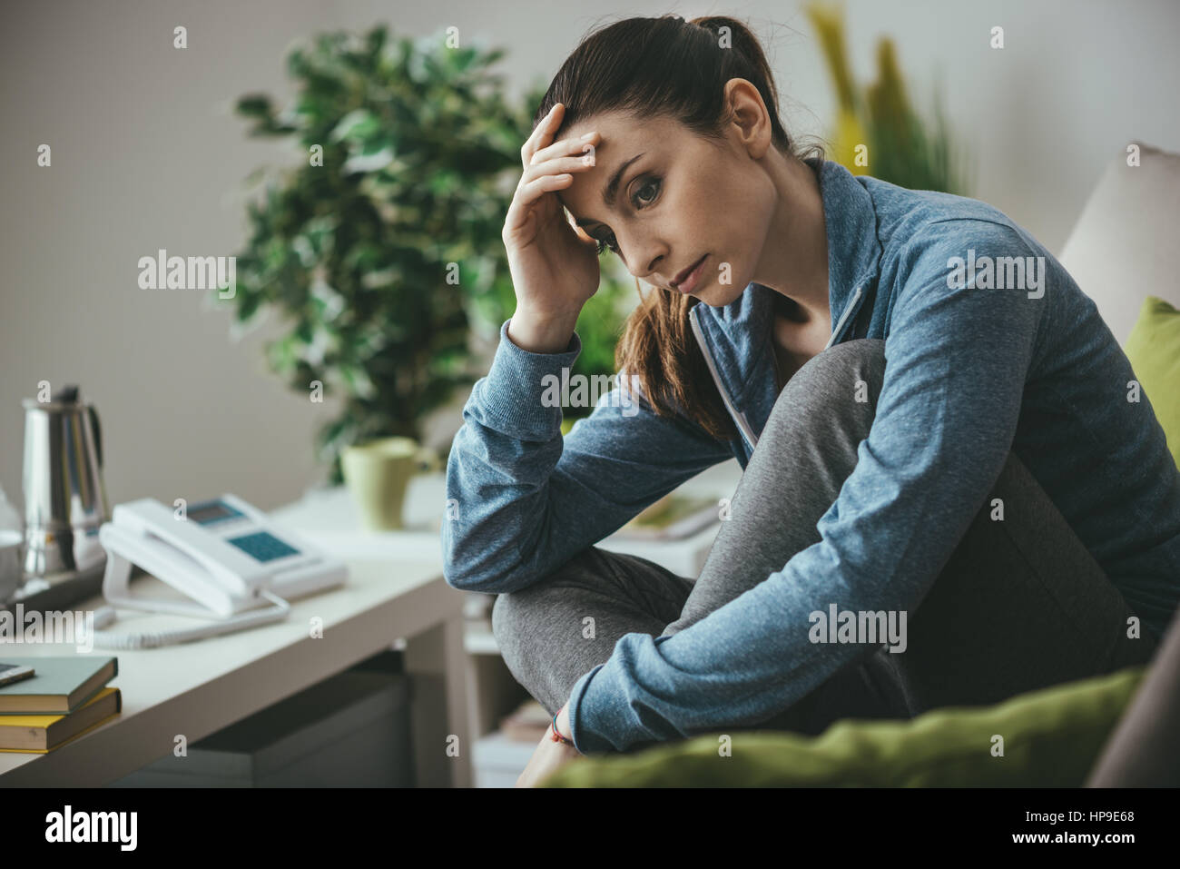 Femme au foyer déprimée triste assis sur le canapé, en regardant et en