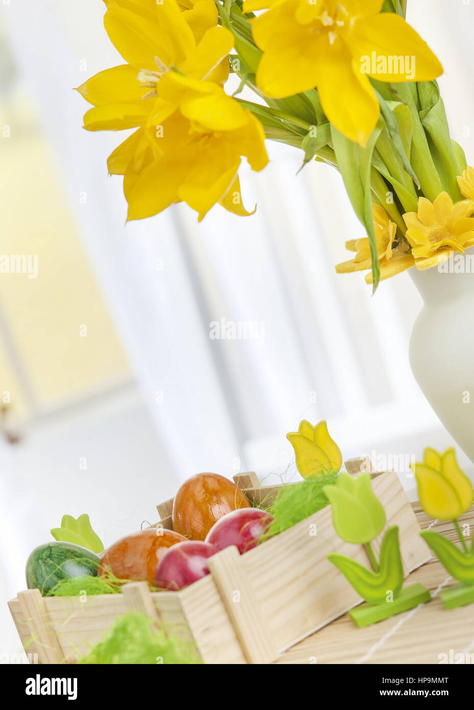 Ostertisch mit bunten eiern gelben und tulpen in nest Banque D'Images