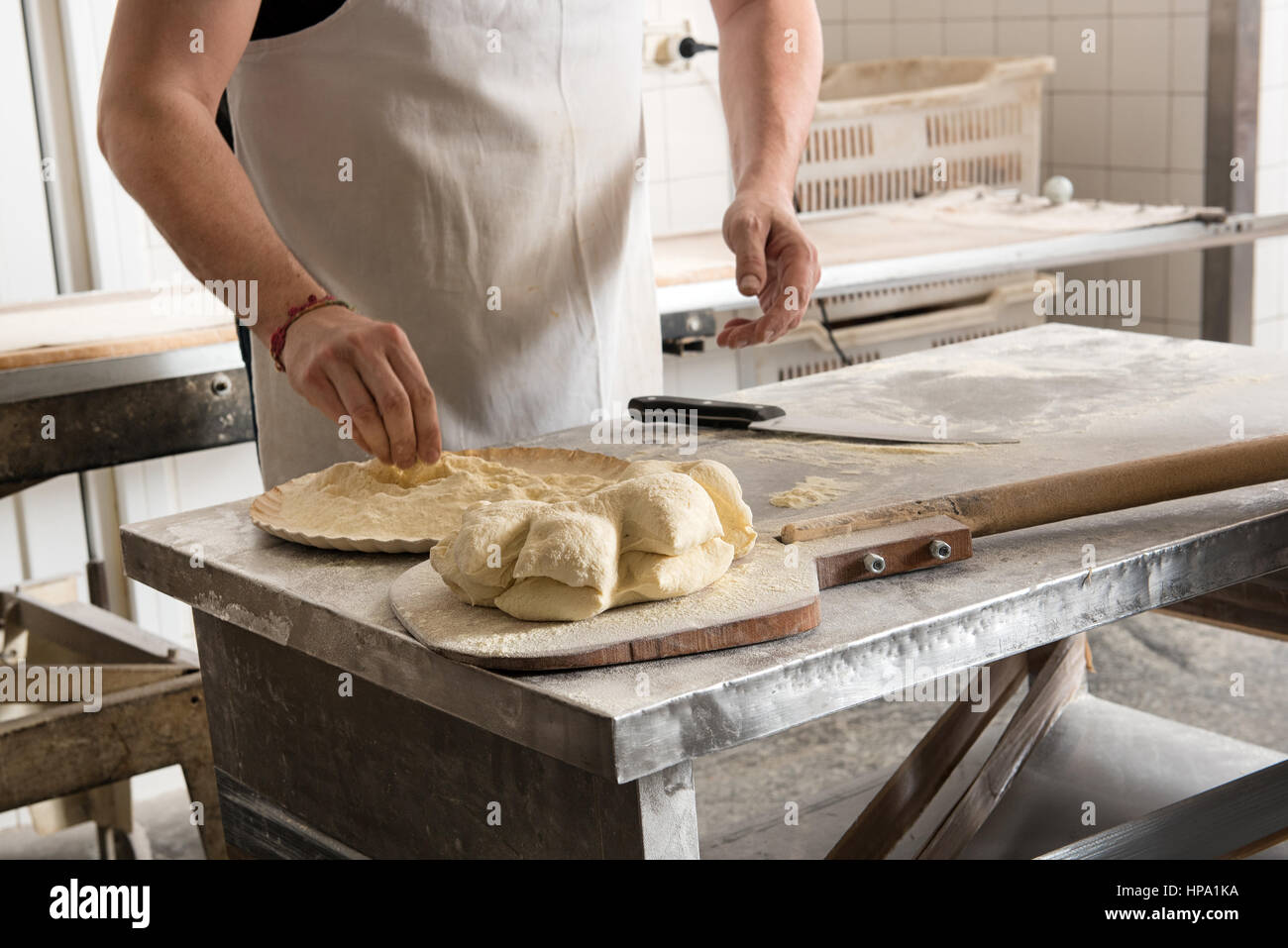 Homme incognito baker working avec la pâte à pizza ou à tarte métal dans une boulangerie Banque D'Images