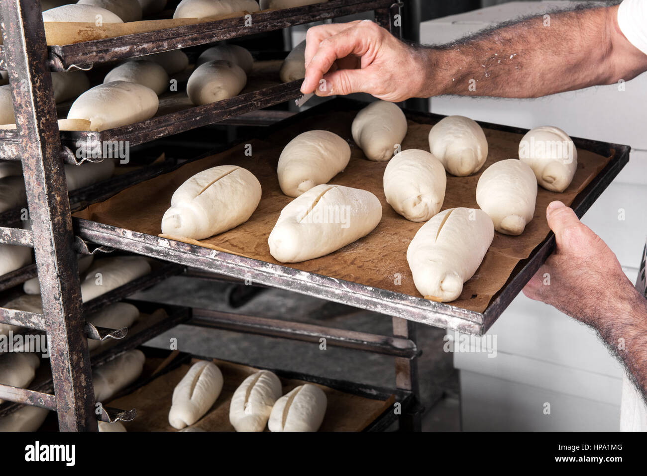 Les mains des hommes de Baker en mettant le plateau métallique avec du pain à l'intérieur du four de boulangerie en stand professionnel Banque D'Images