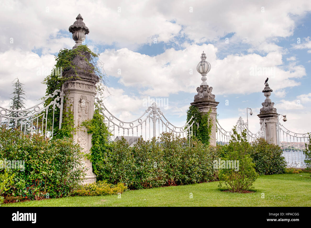 Une porte en fer ornée avec des piliers en pierre revêtus de lierre dans un jardin luxuriant, une partie du palais Dolmabahçe à Istanbul, Turquie. Banque D'Images