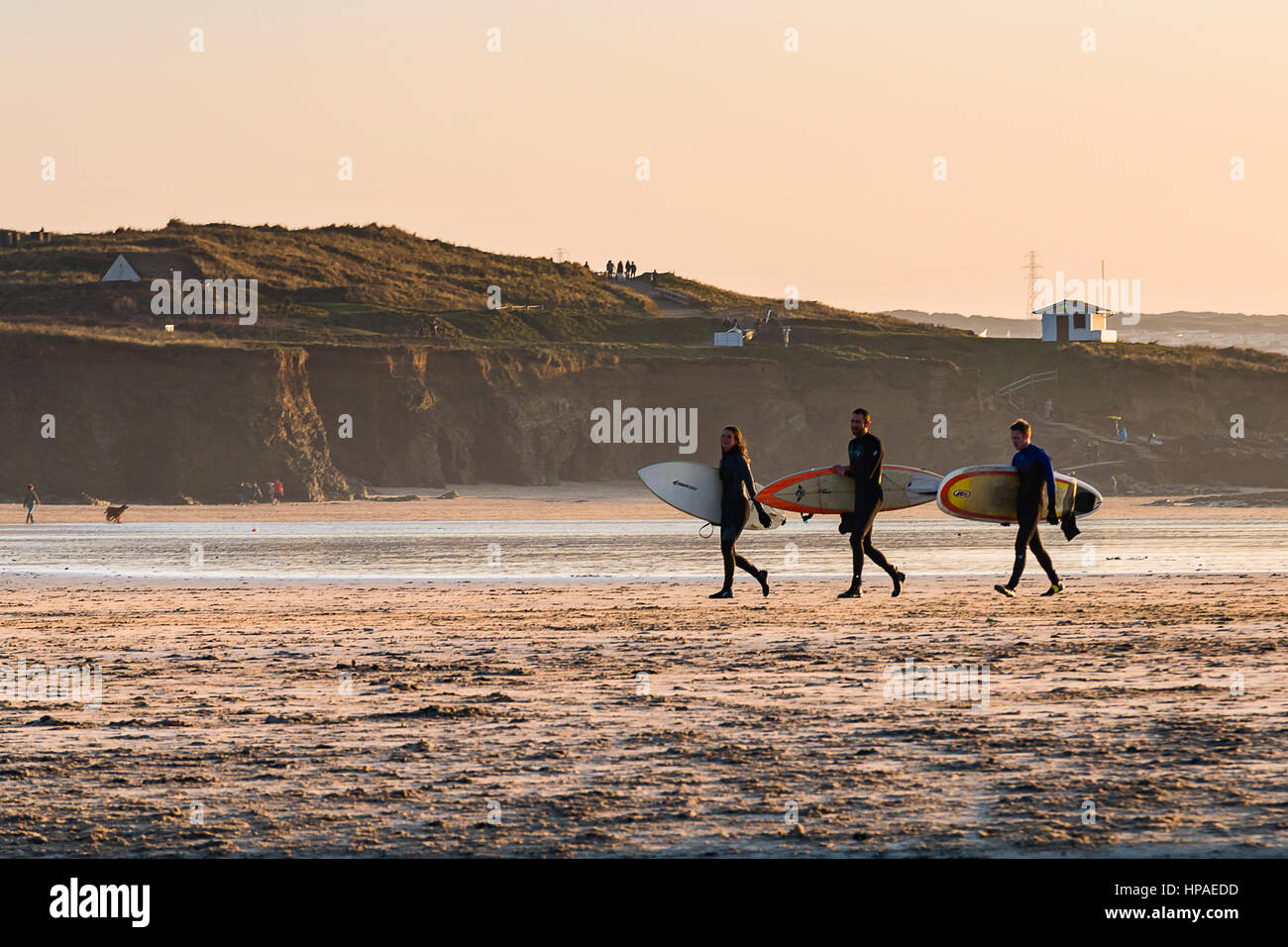 Trio de UK surfeurs de la position le long de la plage de Godrevy Bay à Cornwall sur une belle journée d'hiver, des planches de surf. Banque D'Images