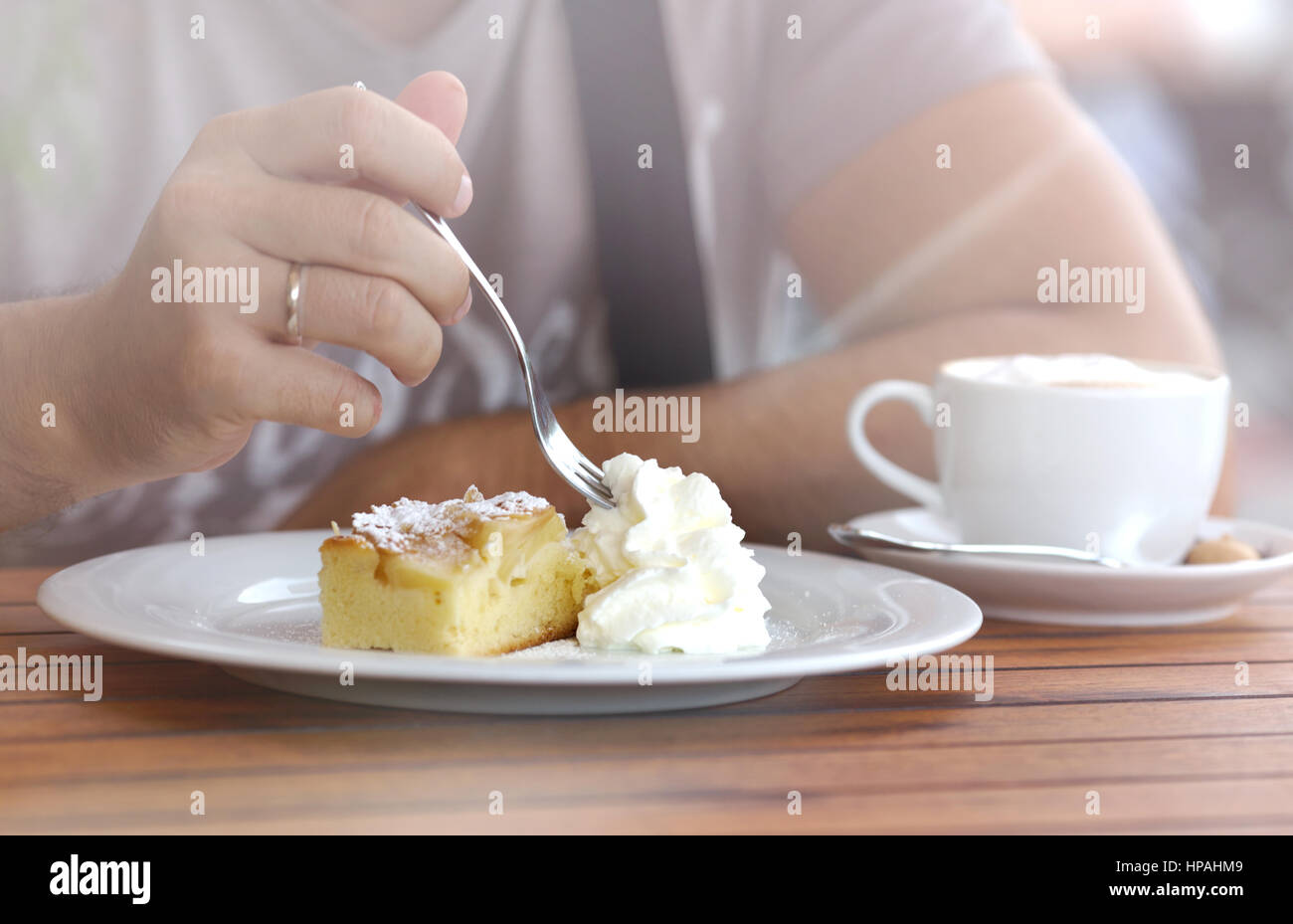 Morceau de gâteau sucré crémeux couper la main d'un homme avec une fourchette. Banque D'Images