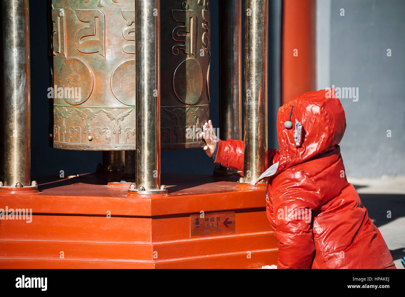 Un jeune garçon en tournant une roue de prière bouddhiste au temple des lamas, Beijing Banque D'Images