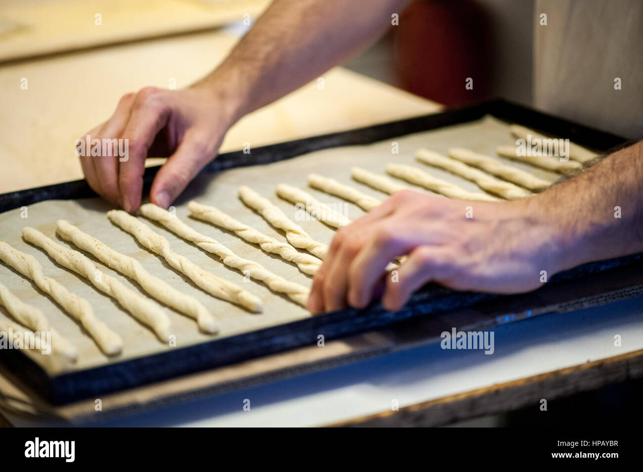 Close-up of male incognito baker mains placer la pâte sur la plaque de cuisson batonnets pour la cuisson au four Banque D'Images