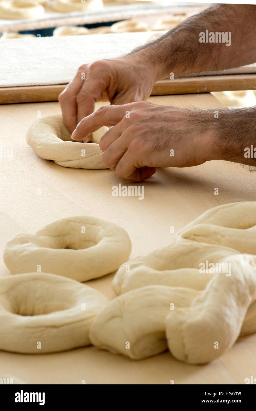 Close-up side view of male baker mains faisant le pain italien frisella formant la pâte en forme de donuts Banque D'Images