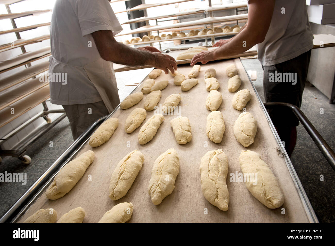 Incognito deux hommes travaillant dans une boulangerie de placer la pâte à pain sur four band Banque D'Images
