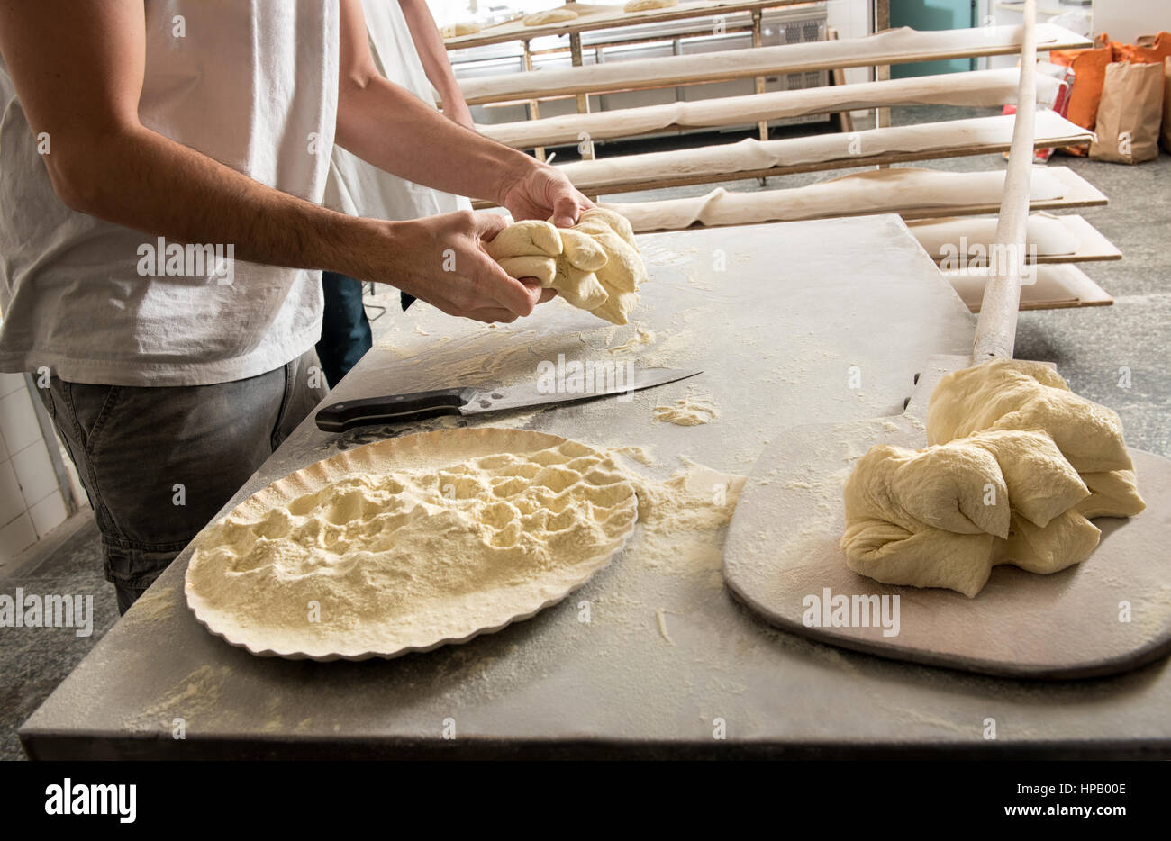 Avec la pâte de travail masculins baker, pan avec la farine et du pain sur peel en bois en premier plan Banque D'Images