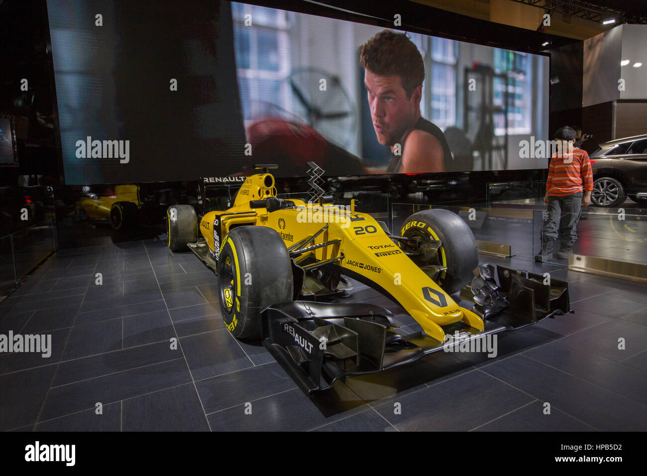 Un jeune garçon regarde une formule jaune 1 voiture de course Renault sur l'affichage à l'Autoshow Banque D'Images