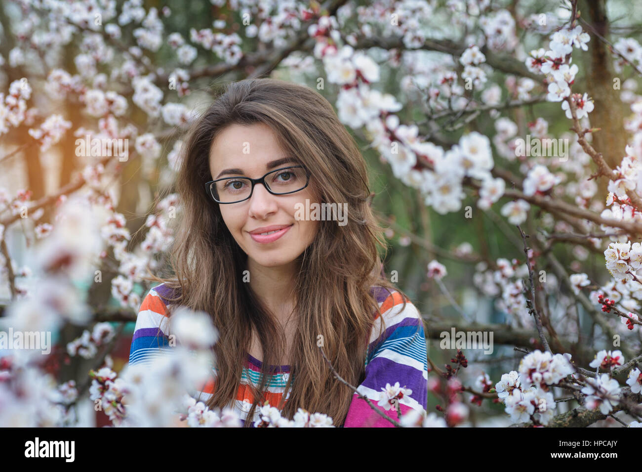 Souriante jeune femme dans le jardin de printemps en fleurs Banque D'Images