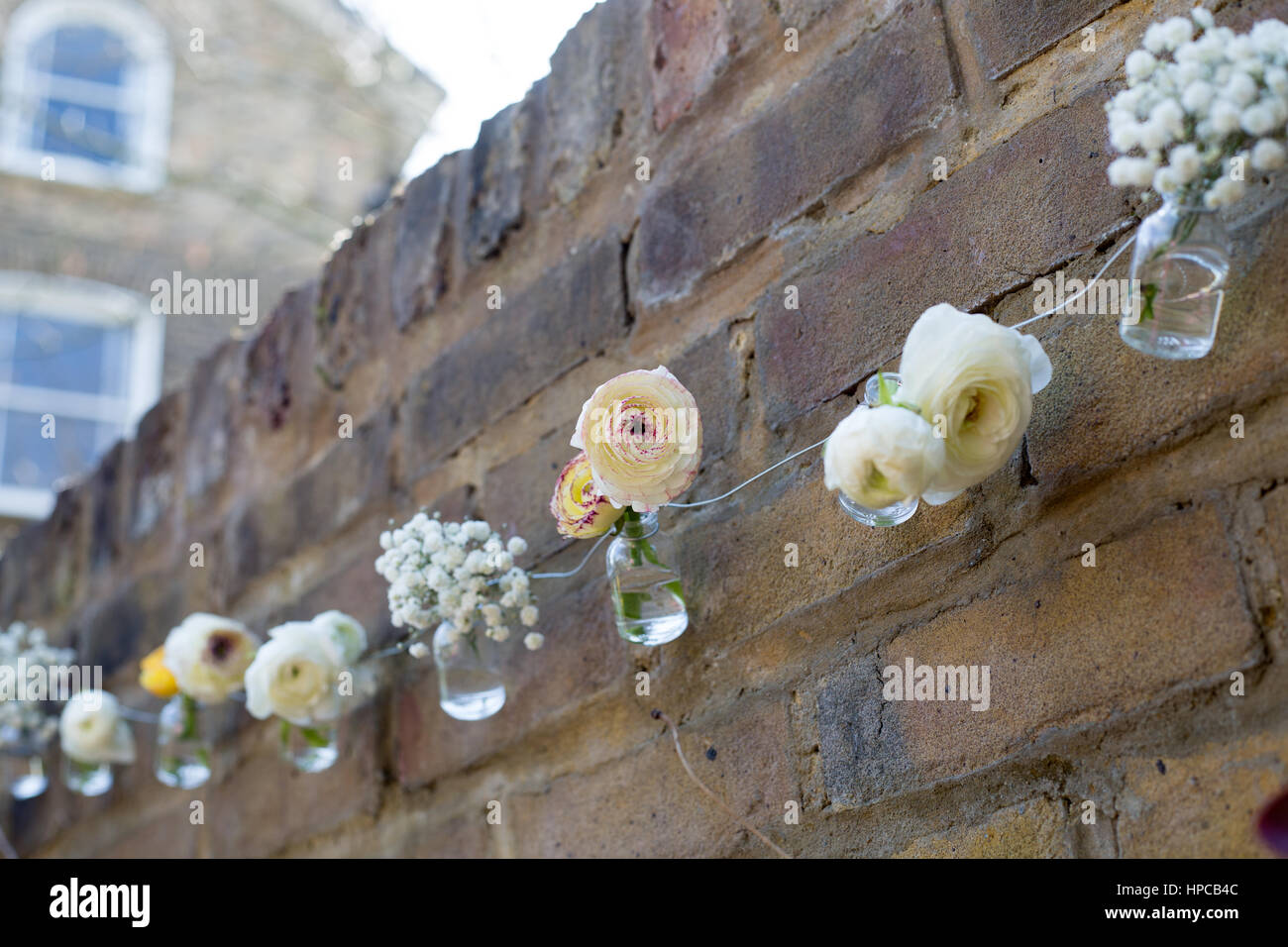 Fleurs blanches et roses décorer un mur de briques Banque D'Images