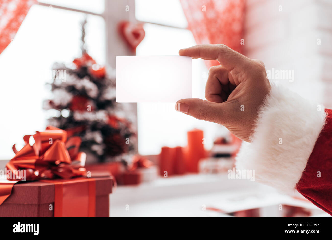 Santa Claus holding a blank business card, Fenêtre et décorations de Noël sur l'arrière-plan Banque D'Images