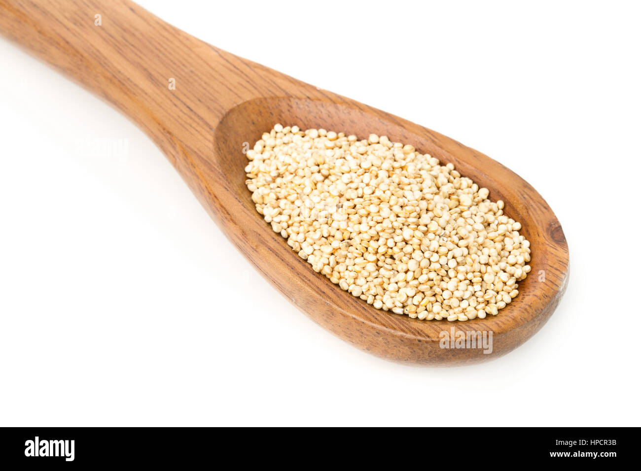 Matières, non cuits, à l'ensemble des graines de quinoa en cuillère en bois sur fond blanc Banque D'Images