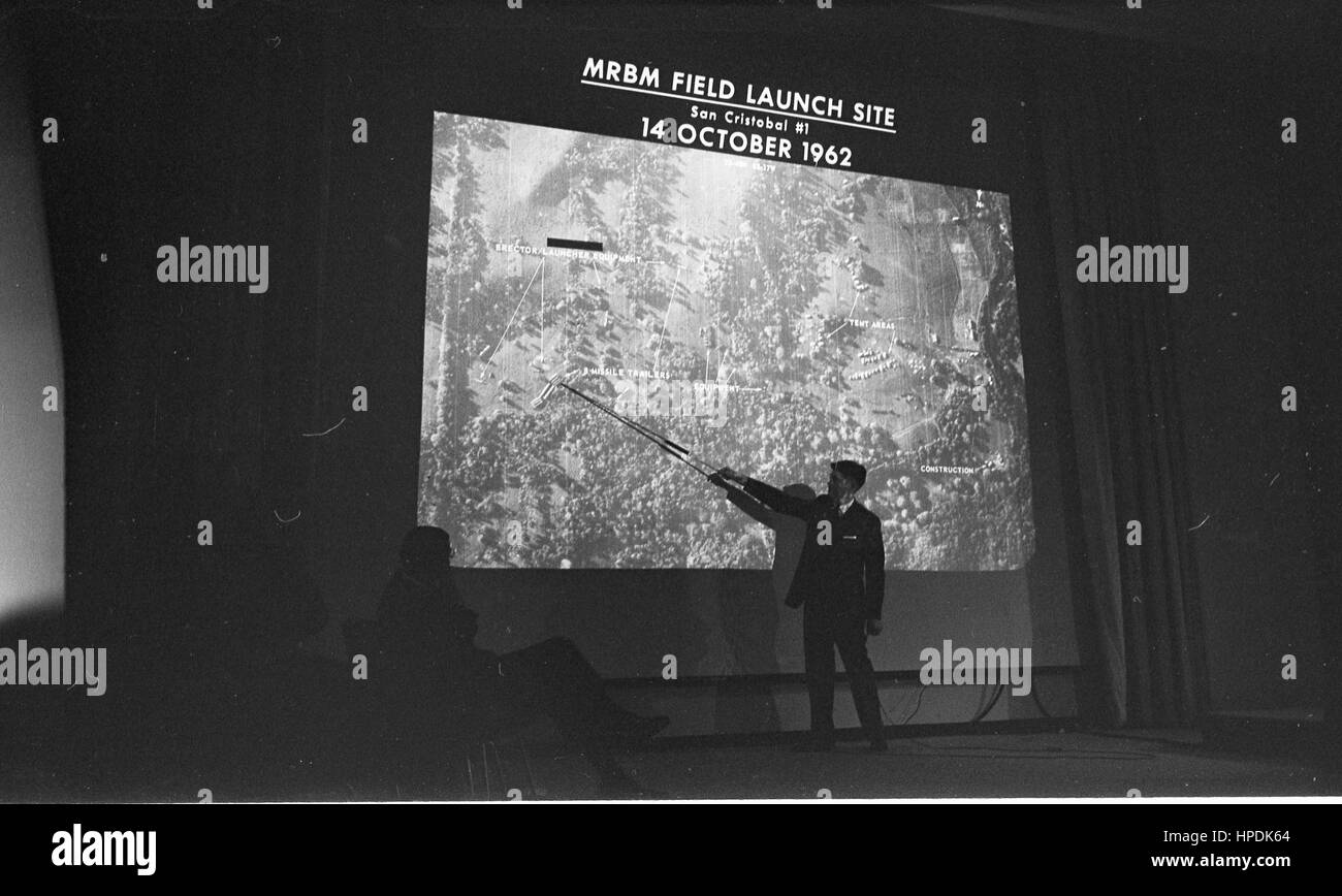 L'homme avec l'aiguille en face d'une diapositive projetée montrant une photo aérienne marqués 'MDomaine de la GPR Site de lancement San Cristobal # 1 14 octobre 1962, à des discussions sur Cuba au département d'État, Washington, DC, 10/14/1962. Banque D'Images
