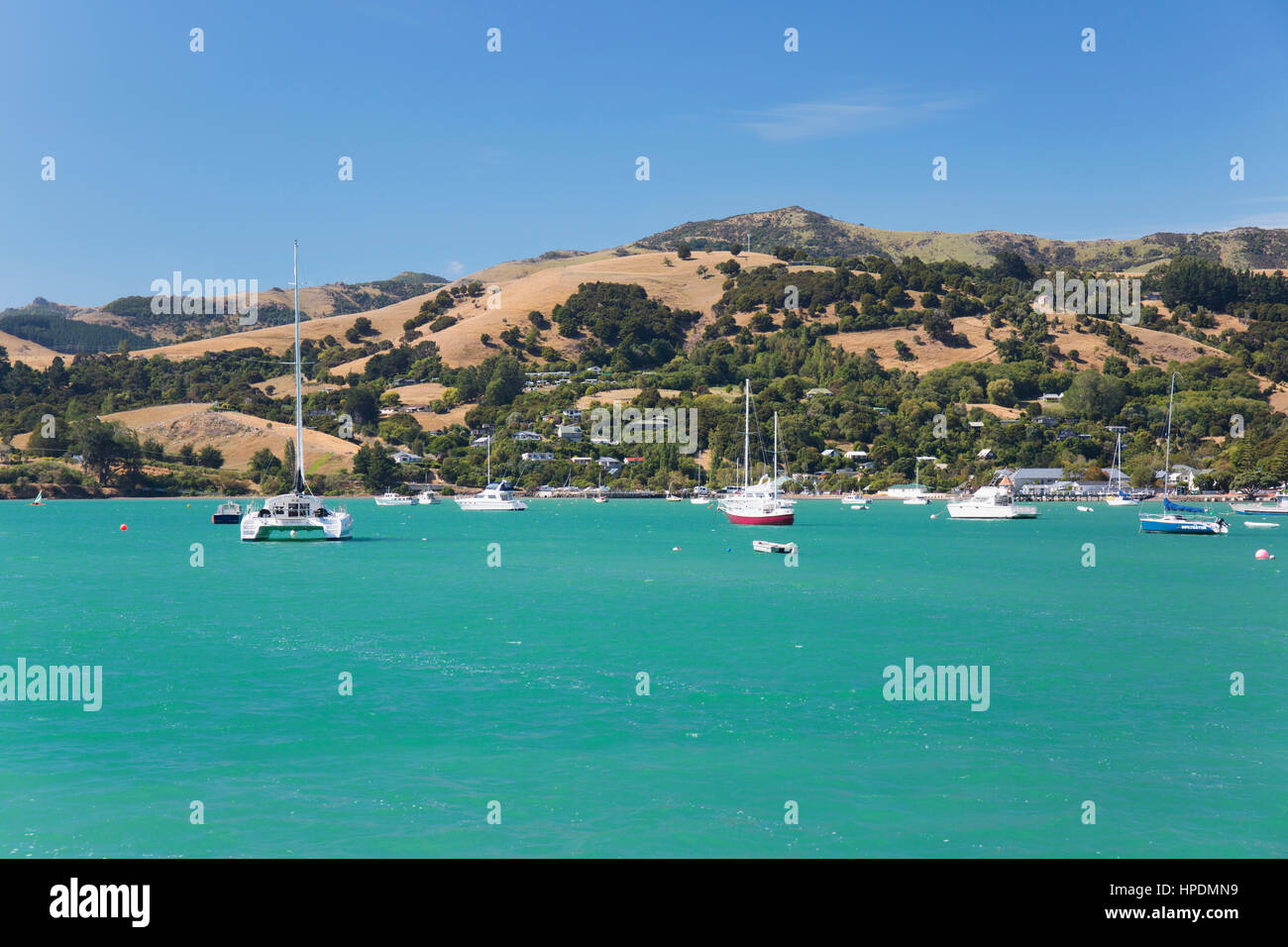 Akaroa, Canterbury, Nouvelle-Zélande. Vue sur les eaux turquoises d'Akaroa Harbour pour les collines de la péninsule de Banks. Banque D'Images